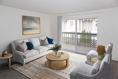 A living room with a grey couch, a wooden coffee table, and a painting on the wall.